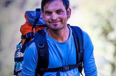 Trek guide smiling with backpack during mountain hike in Dharamshala