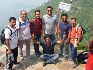 Group of trekkers posing at a Himalayan viewpoint with a “Reduce Plastic” signboard