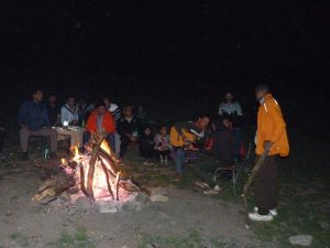 Trekkers sitting around a bonfire at a campsite in the Himalayas at night