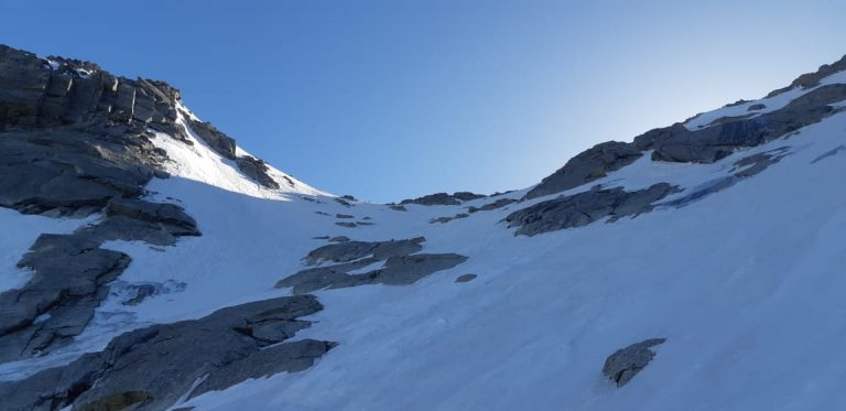 a snow covered mountain with rocks and blue sky