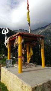 Small temple at Triund Top with prayer flags and mountain backdrop