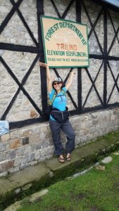 Trekker posing with the Forest Department Triund signboard at 2,875 meters elevation in Himachal Pradesh