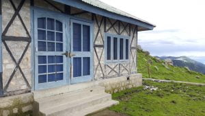 Mountain rest house with blue doors in the Dhauladhar range, Himachal Pradesh