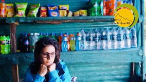 Trekker resting at a small shop stocked with snacks and drinks on a trail near McLeod Ganj, Himachal Pradesh