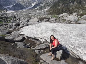 Trekker sitting on a rock near snow patches during Kareri Lake Trek in Himachal Pradesh