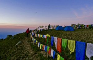 Colorful prayer flags and tents at Triund Camp during sunset near McLeod Ganj, Dharamshala
