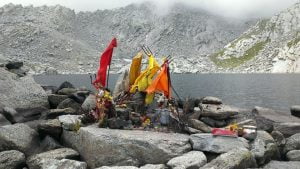 Sacred shrine on the rocky shore of Nag Dal Lake with mist-covered Himalayan mountains in the background