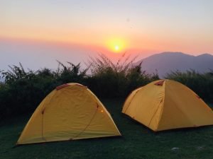 Orange trekking tents under sunset sky on a hillside in Dharamshala