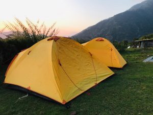 Orange trekking tents under sunset sky on a hillside in Dharamshala