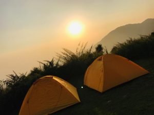 Orange trekking tents under sunset sky on a hillside in Dharamshala