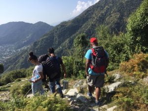 Trekkers descending a trail with panoramic views of the Dhauladhar range during Laka Glacier Trek