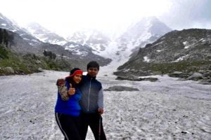 Smiling couple posing on snowy trail during Laka Glacier Trek in Himachal