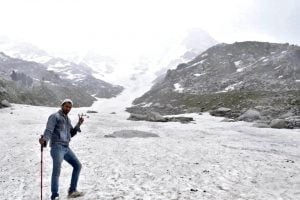 Trekker posing at Laka Glacier surrounded by snow and rocky peaks in Himachal Pradesh