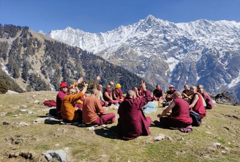 a group of people sitting on the ground in front of a mountain