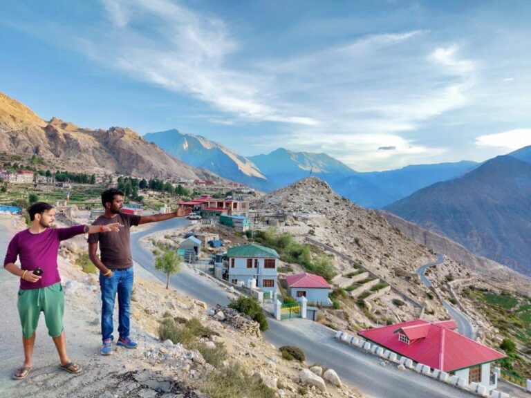a men standing on a hill with mountains in the background