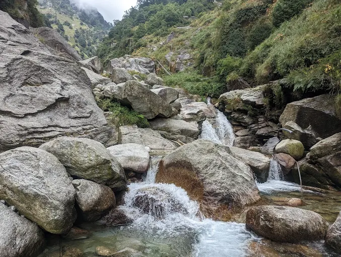 Hikers resting near Gallu Waterfall on a forest trail above Dharamkot