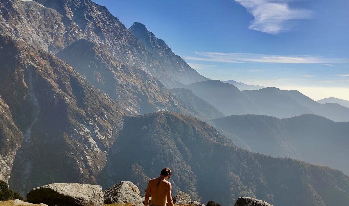 Trekker standing at Kundli Pass with Dhauladhar peaks in the background