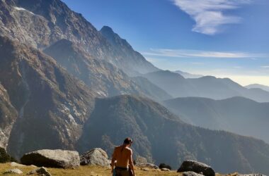 Trekker standing at Kundli Pass with Dhauladhar peaks in the background