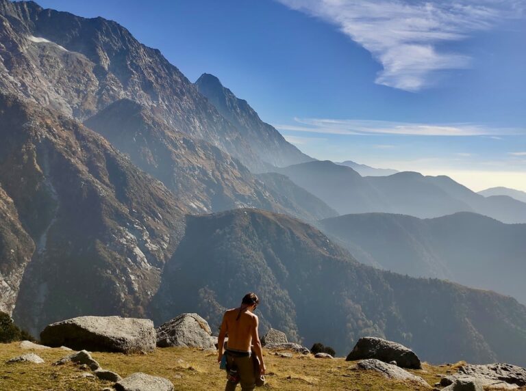 Trekker standing at Kundli Pass with Dhauladhar peaks in the background