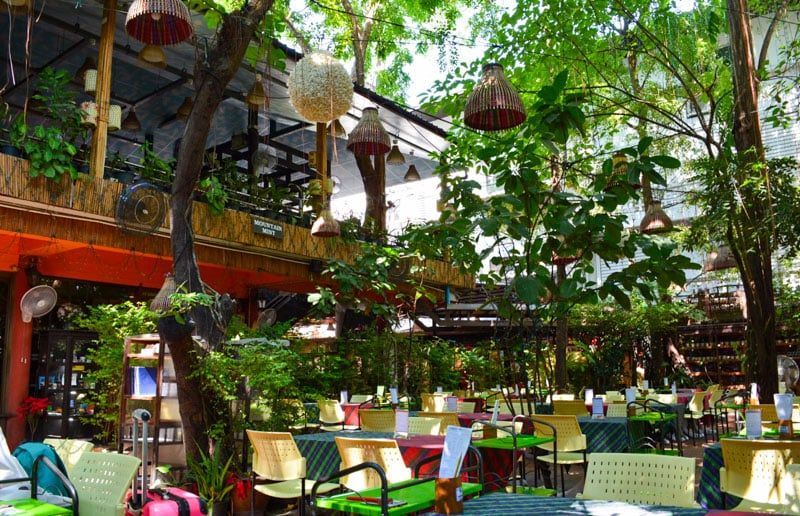 Outdoor seating area at a vibrant cafe in Dharamshala surrounded by greenery
